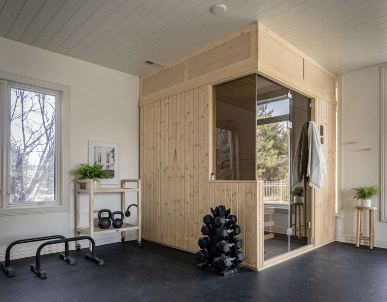 Modern wellness room with custom cut sauna and weigh lifting equipment